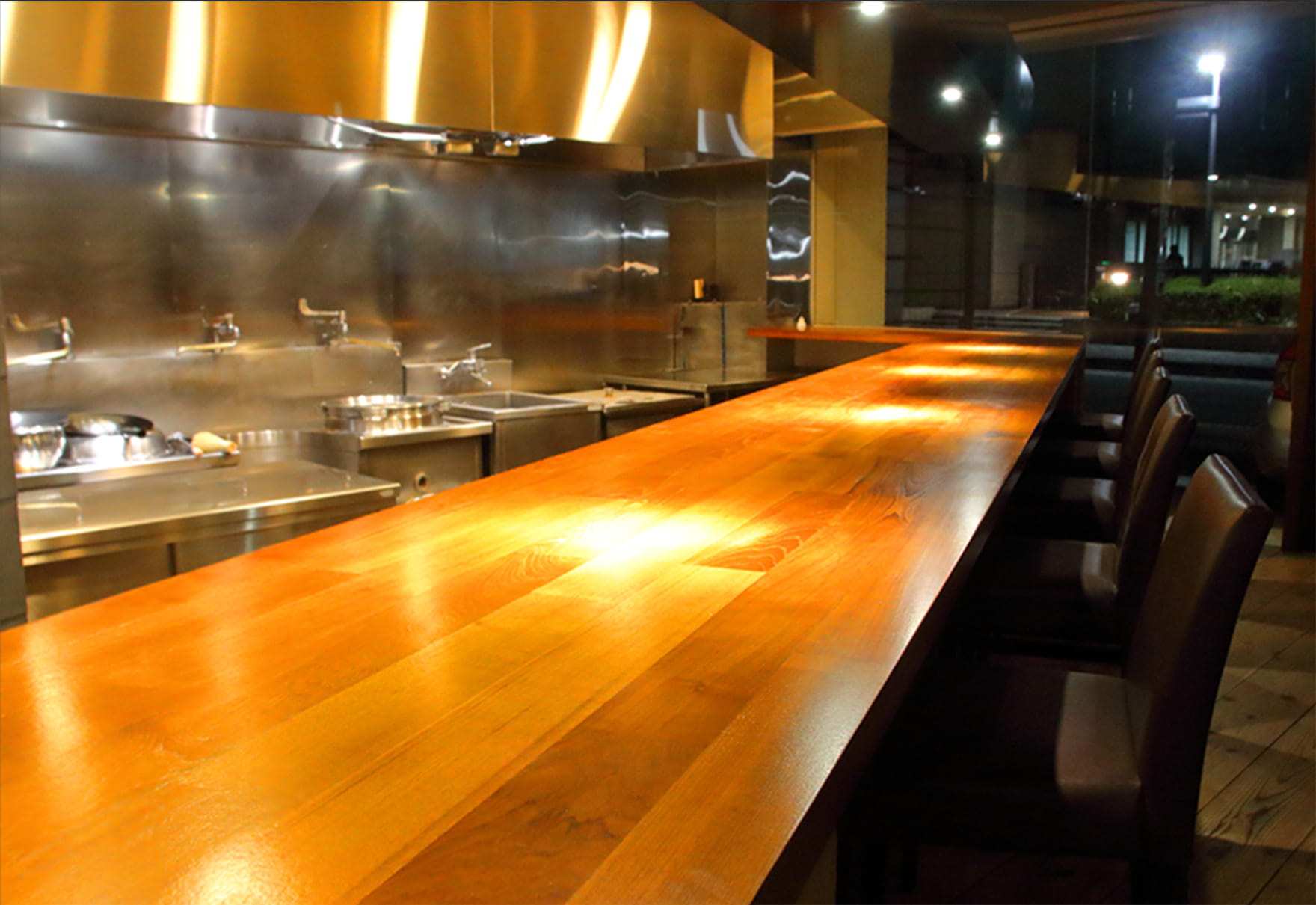 オープンキッチンを眺められる木目カウンター席の店内